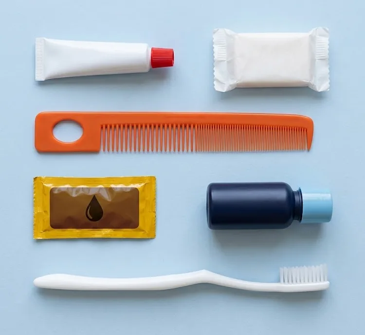 The six items in the basic kit laid out: toothpaste, wrapped soap, orange comb, hair oil sachet, shampoo bottle and toothbrush